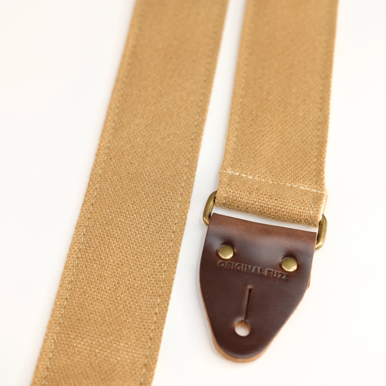 End-tab detail view of guitar strap in tan woven fabric with brown leather end-tab. Made in Nashville by Original Fuzz.