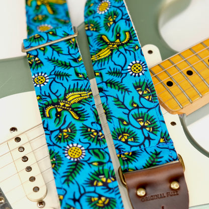 Wide view of guitar strap in blue, yellow, and green botanical African wax print fabric with brown leather end-tab. Made in Nashville by Original Fuzz.