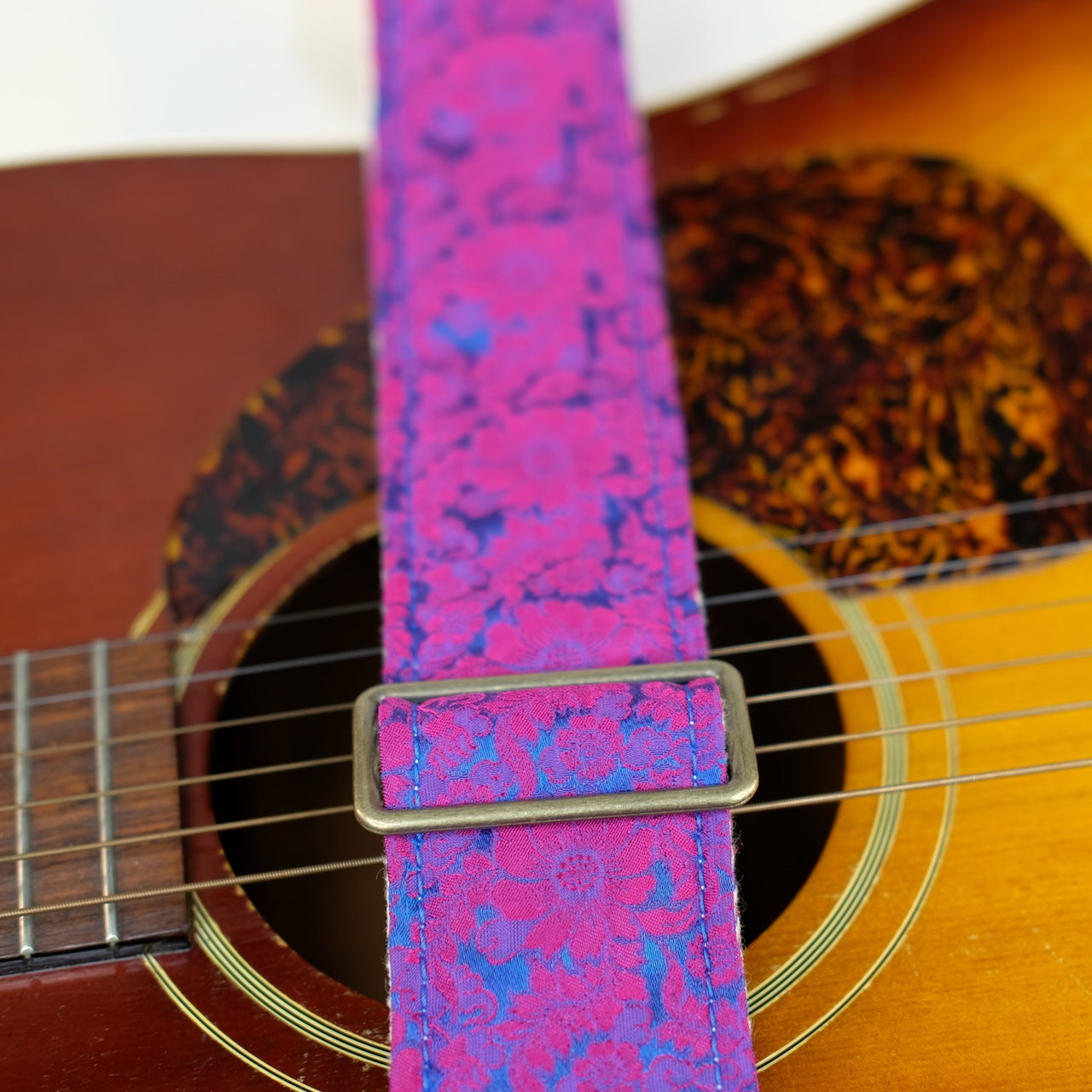 Buckle detail of guitar strap in pink and blue silk floral fabric with black leather end-tab. Made in Nashville by Original Fuzz.