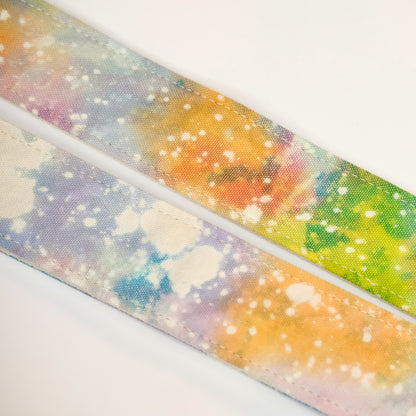 Fabric detail view of guitar strap in multi-colored over cream base hand-dyed canvas fabric with brown leather end-tab. Made in Nashville by Original Fuzz.