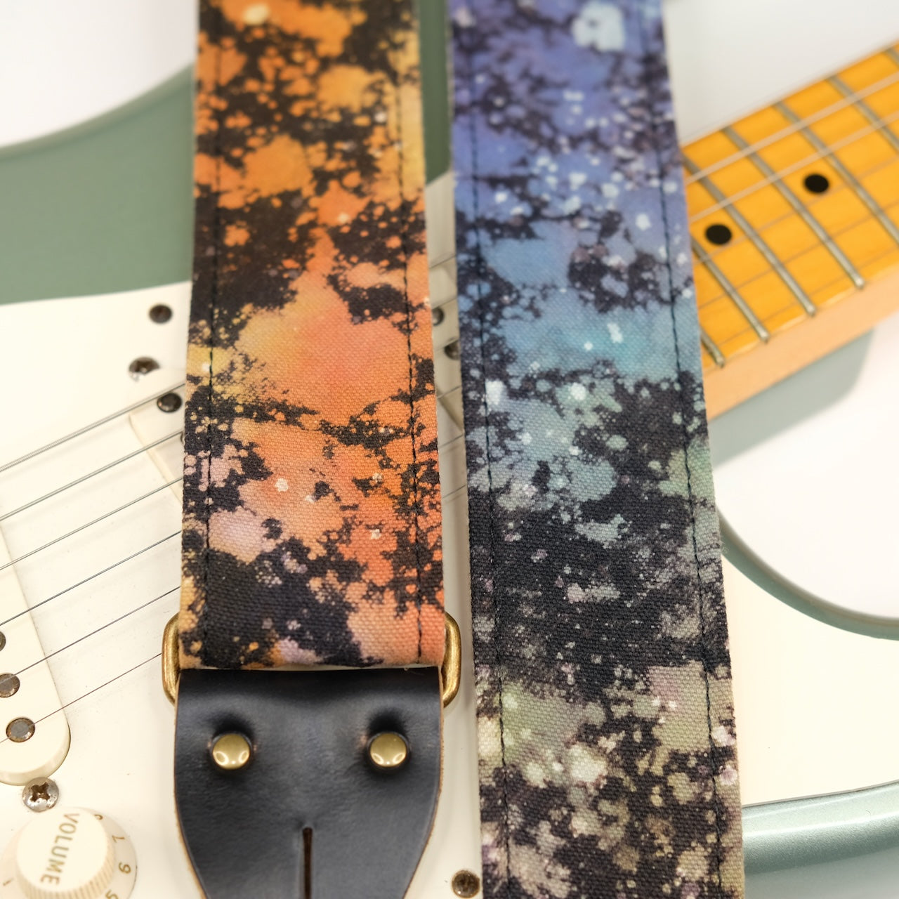 Wide view of guitar strap in multi-colored over black base hand-dyed canvas fabric with black leather end-tab. Made in Nashville by Original Fuzz.