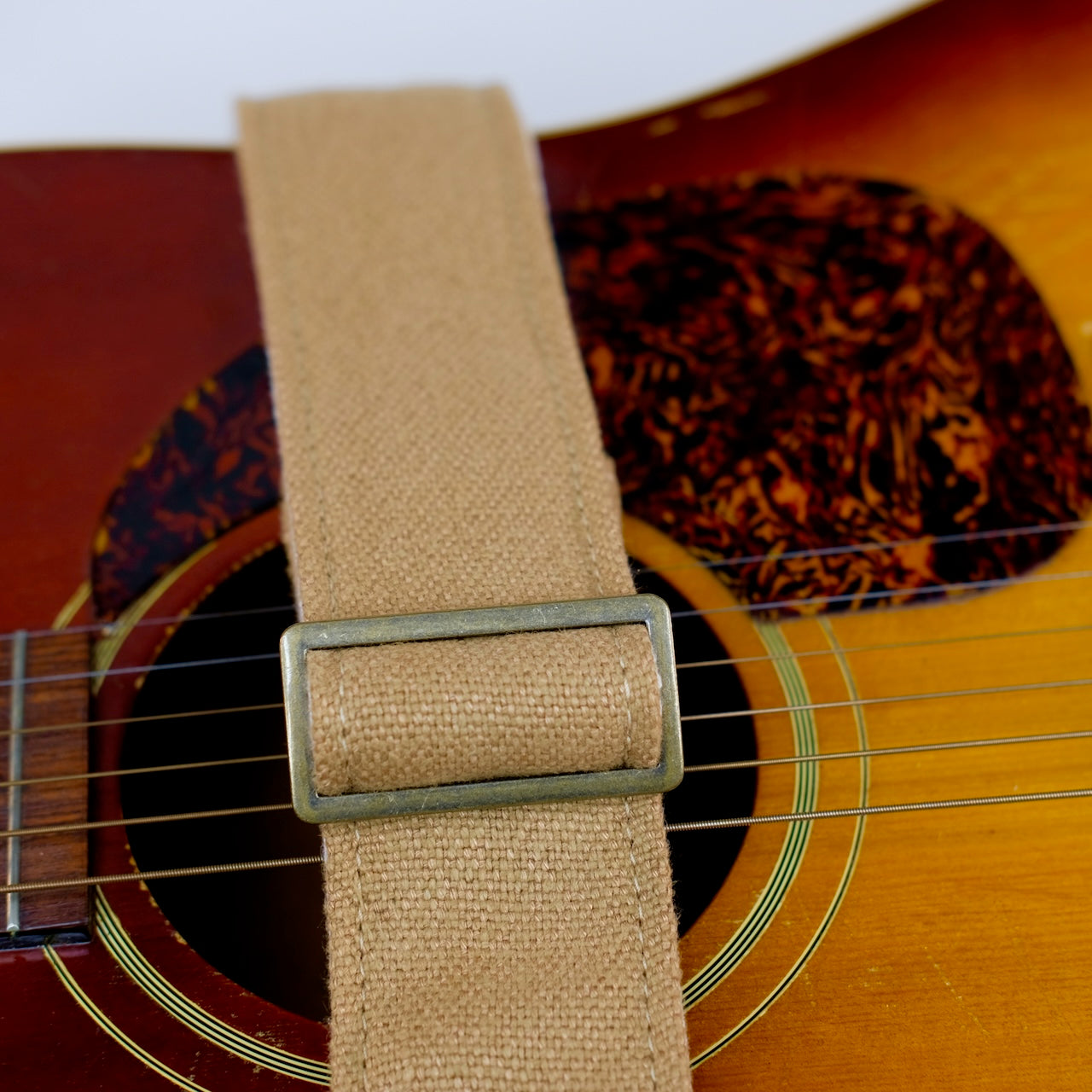 Buckle detail of guitar strap in tan woven fabric with brown leather end-tab. Made in Nashville by Original Fuzz.