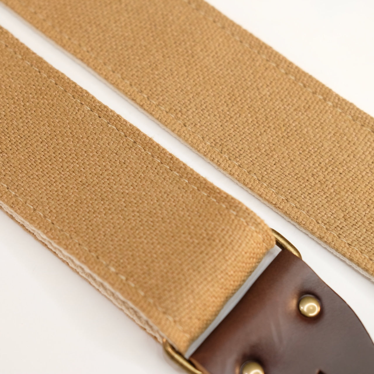 Fabric detail view of guitar strap in tan woven fabric with brown leather end-tab. Made in Nashville by Original Fuzz.