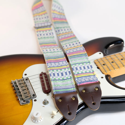 Wide view of guitar strap in white, blue, and green geometric woven fabric with brown leather end-tab. Made in Nashville by Original Fuzz.