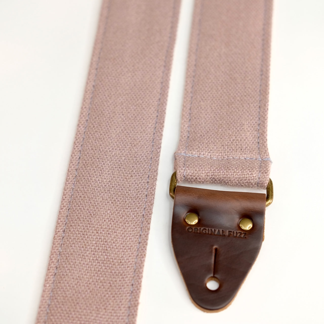 End-tab detail view of guitar strap in dusty pink-purple woven fabric with brown leather end-tab. Made in Nashville by Original Fuzz.