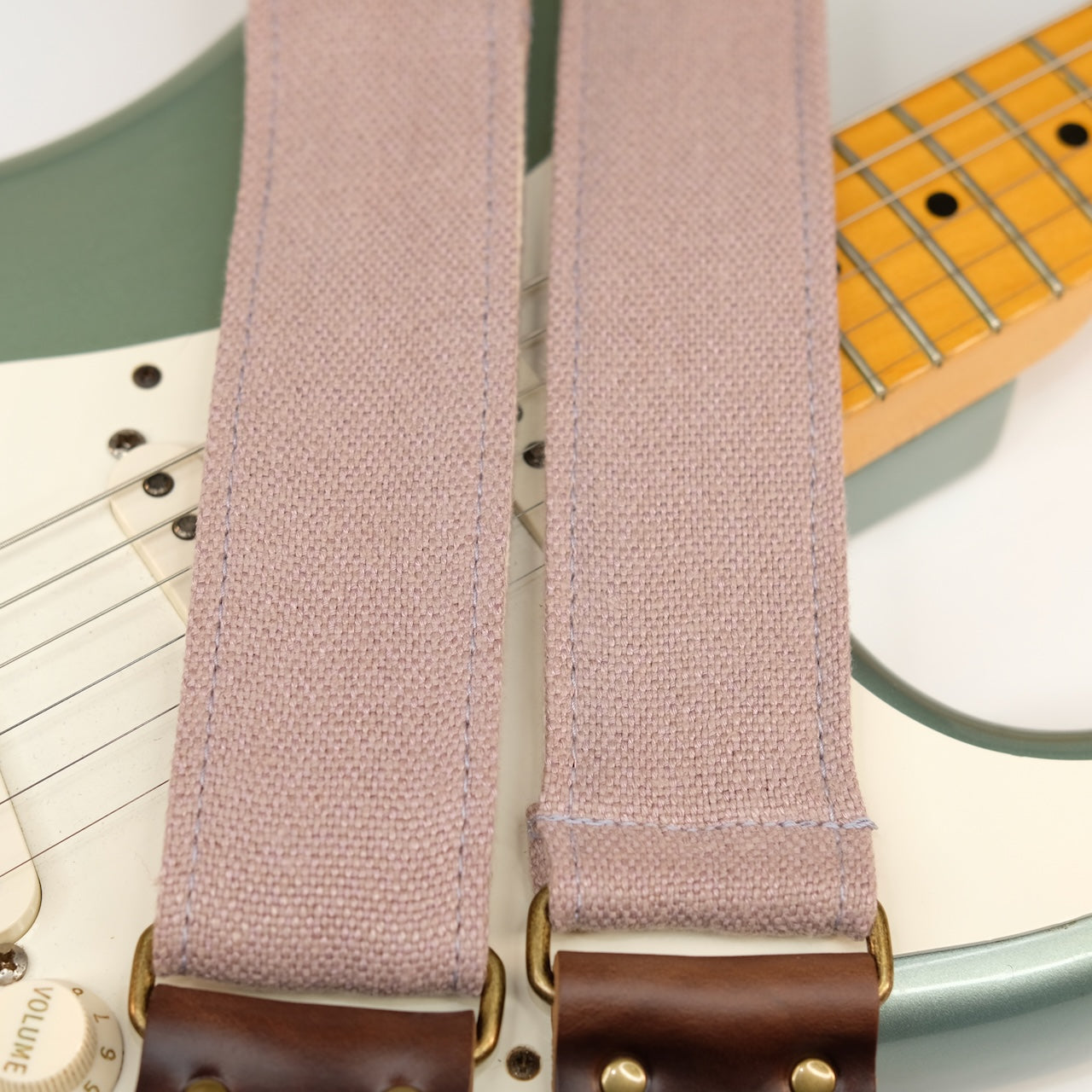 Wide view of guitar strap in dusty pink-purple woven fabric with brown leather end-tab. Made in Nashville by Original Fuzz.