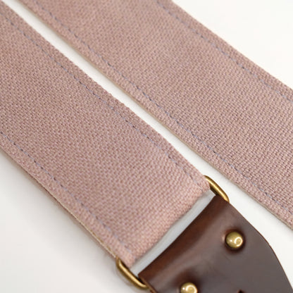 Fabric detail view of guitar strap in dusty pink-purple woven fabric with brown leather end-tab. Made in Nashville by Original Fuzz.