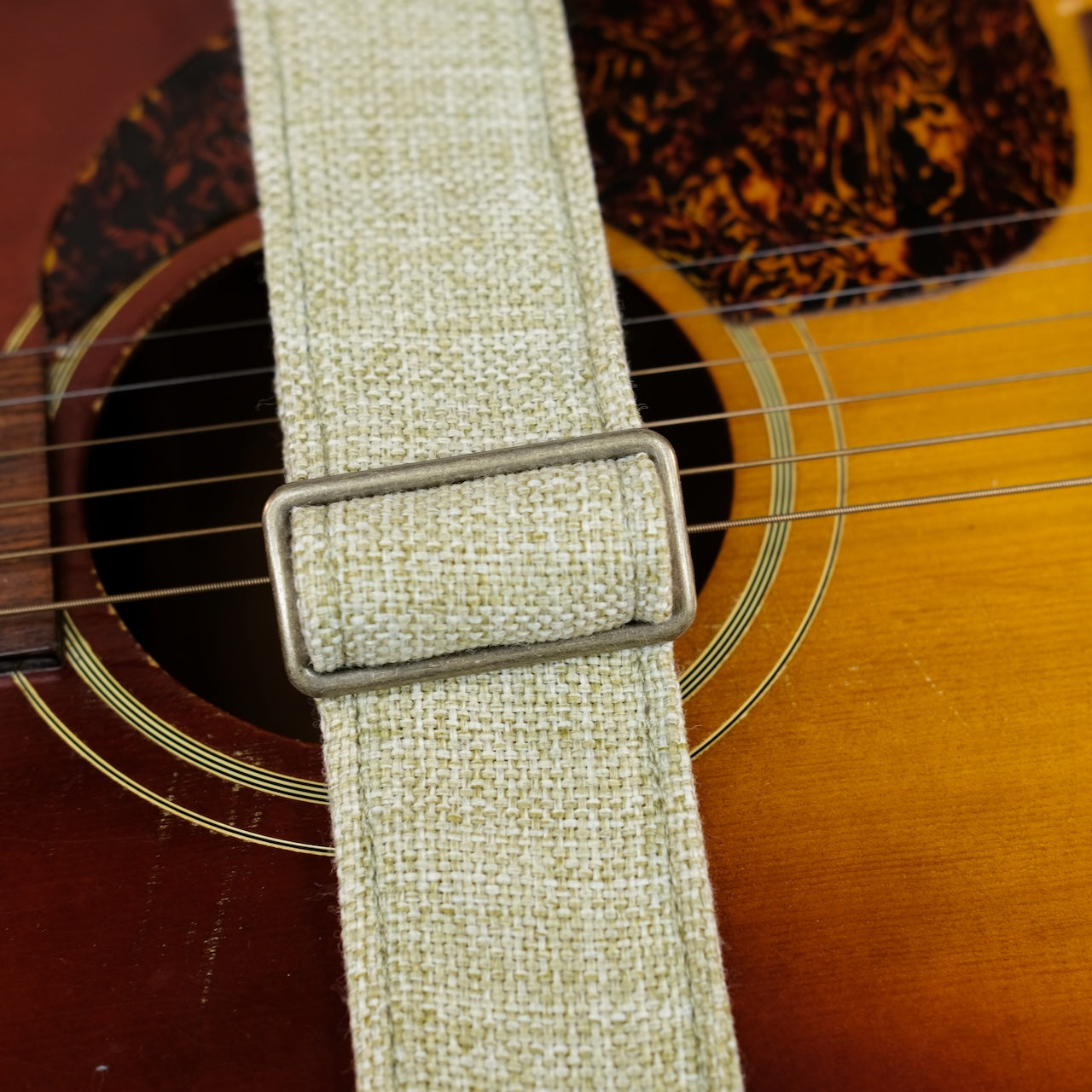 Buckle detail of guitar strap in green and cream woven fabric with brown leather end-tab. Made in Nashville by Original Fuzz.