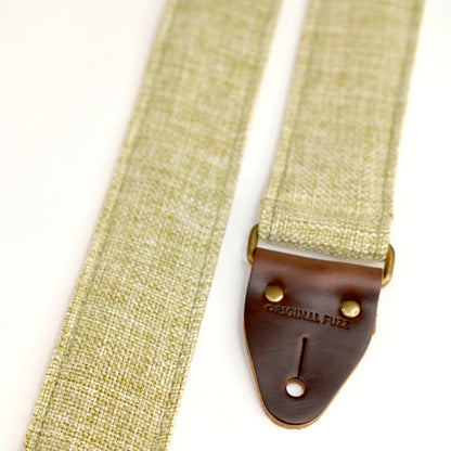 End-tab detail view of guitar strap in green and cream woven fabric with brown leather end-tab. Made in Nashville by Original Fuzz.